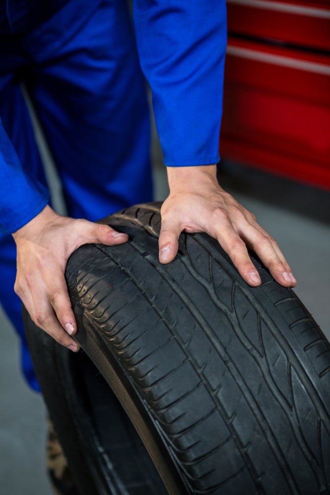 Selling Your Business Requires Advance Planning. Here a technician is rolling tire toward car.